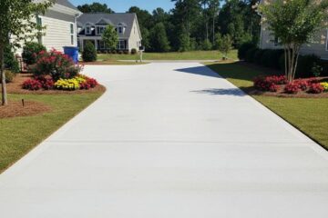 Newly installed concrete driveway in a suburban setting with landscaping